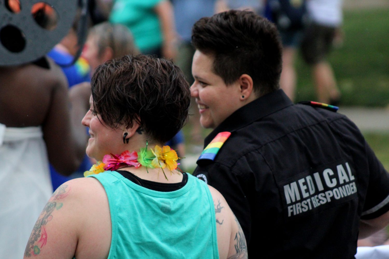 Image of two people wearing rainbow accessories facing away from the camera and talking