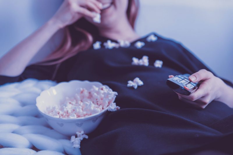 Photo of woman eating popcorn on her bed or couch