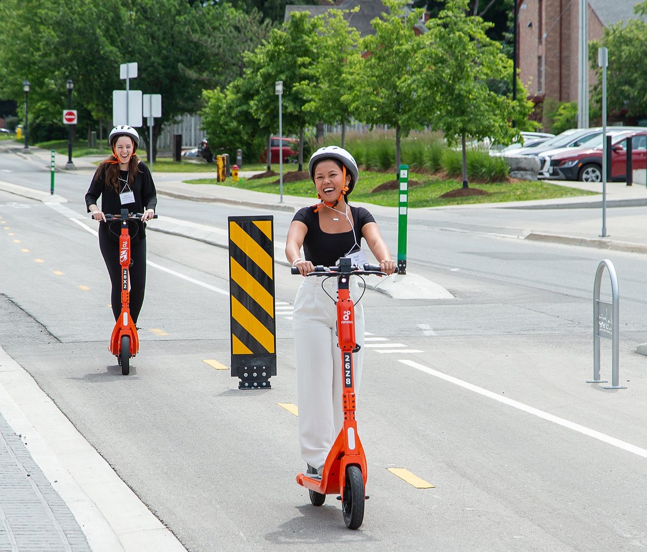 Two people scootering down the road on electric scooters